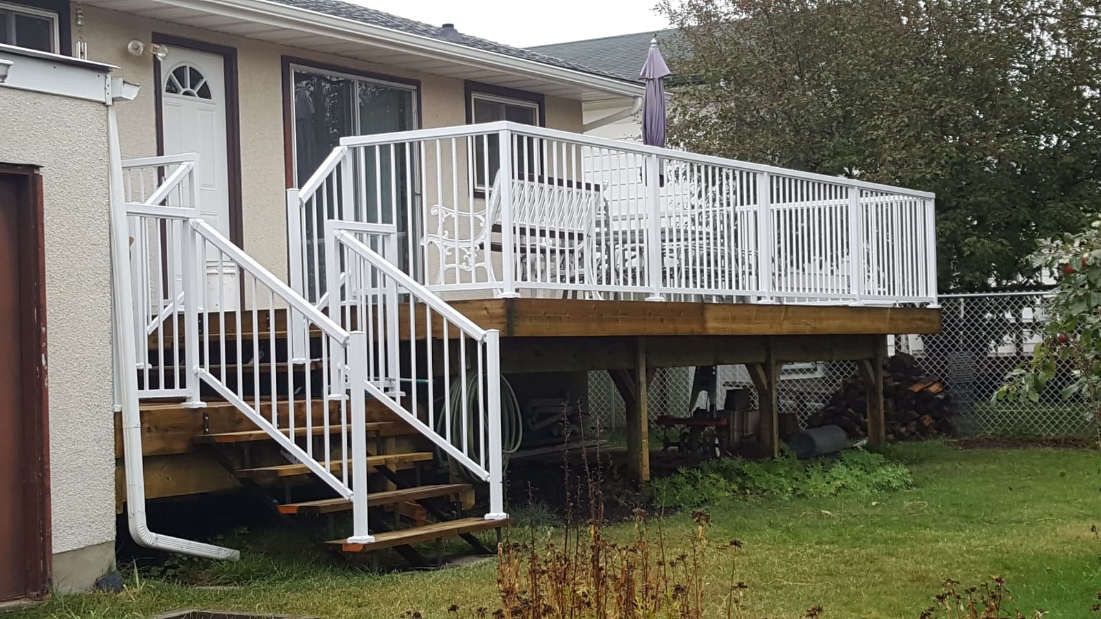 A finished raised deck with white railings and stairs.