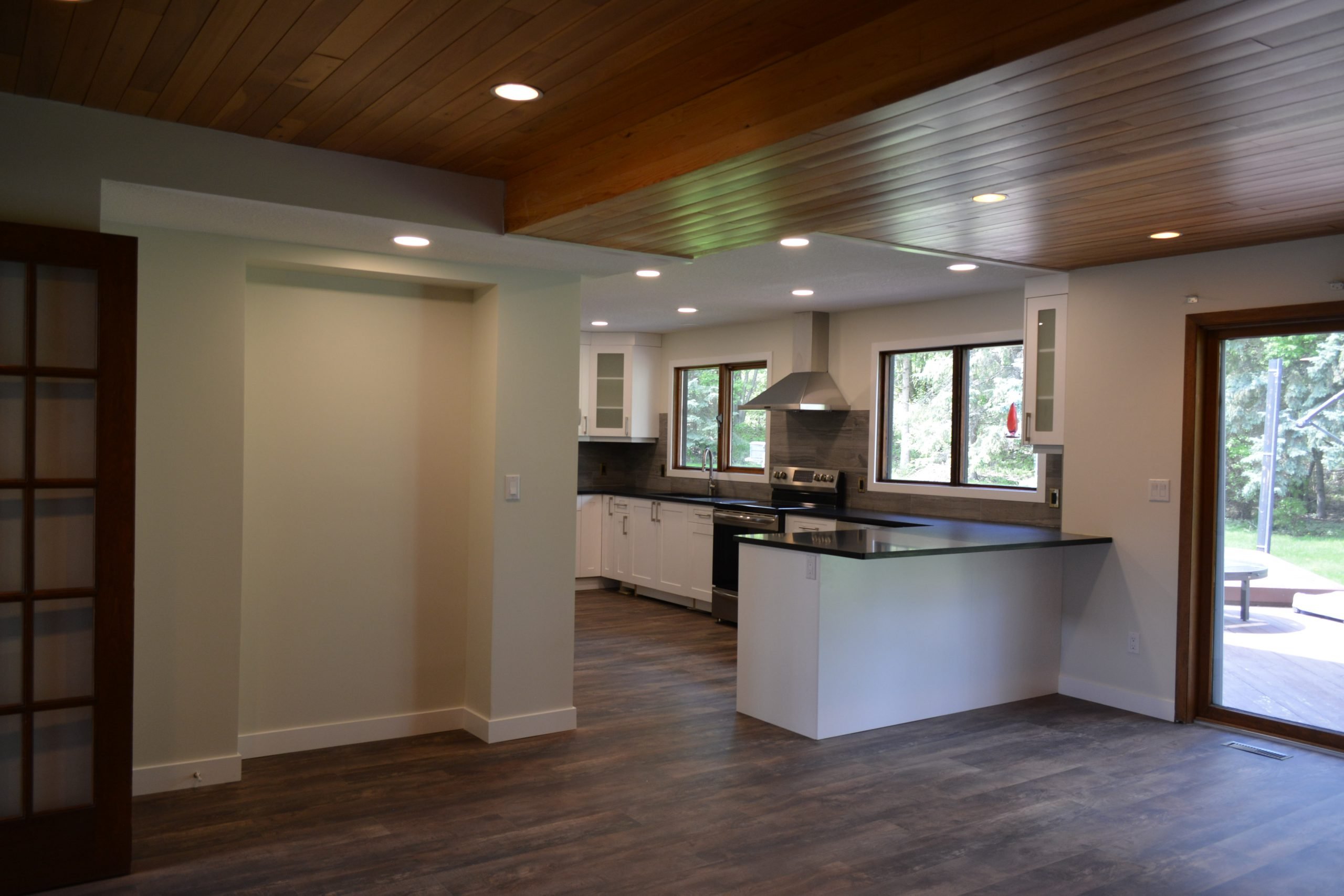 An open-plan basement kitchen with a wood-slat ceiling and a walkout.