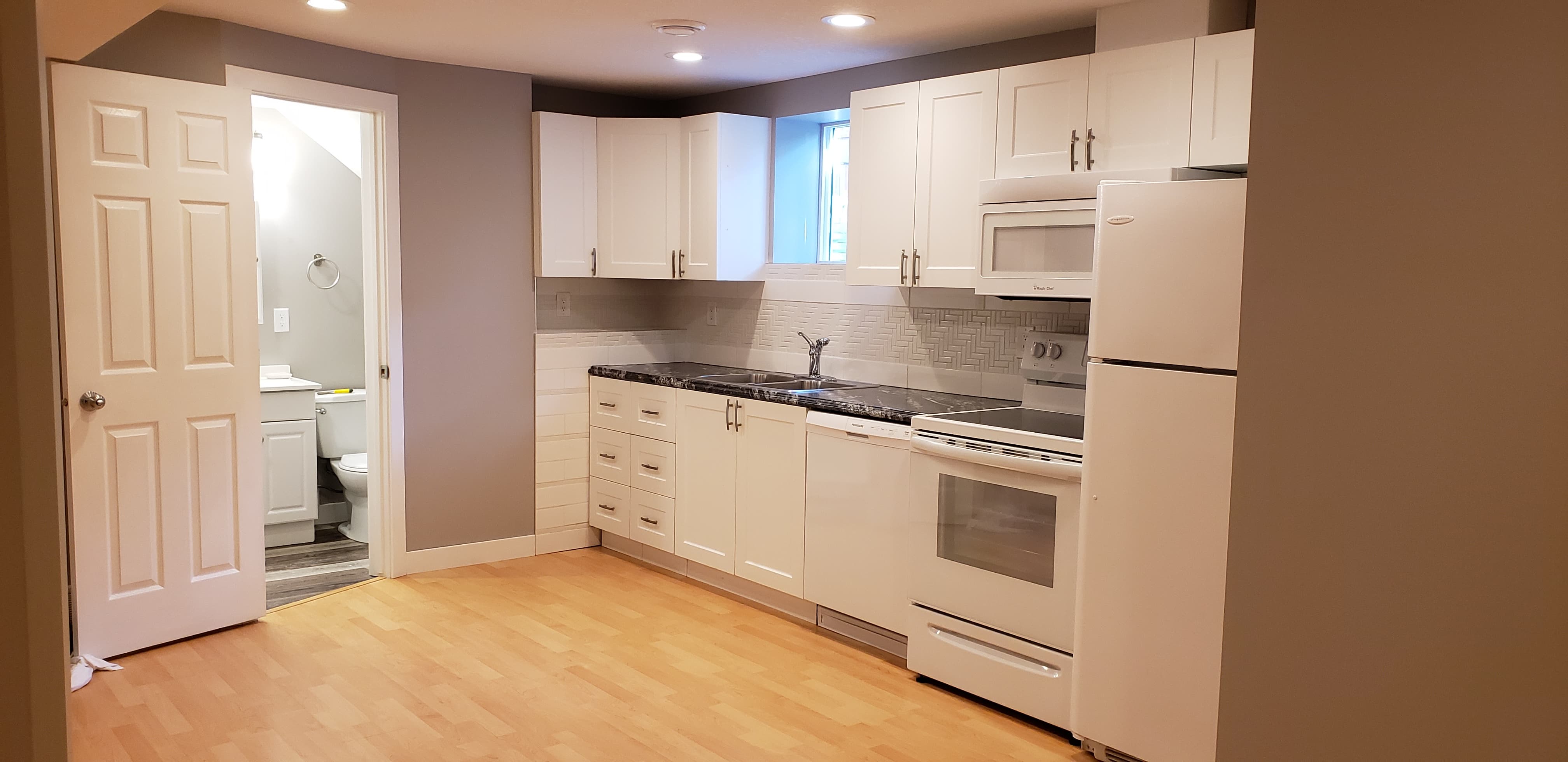 A finished basement kitchen beside a new bathroom.