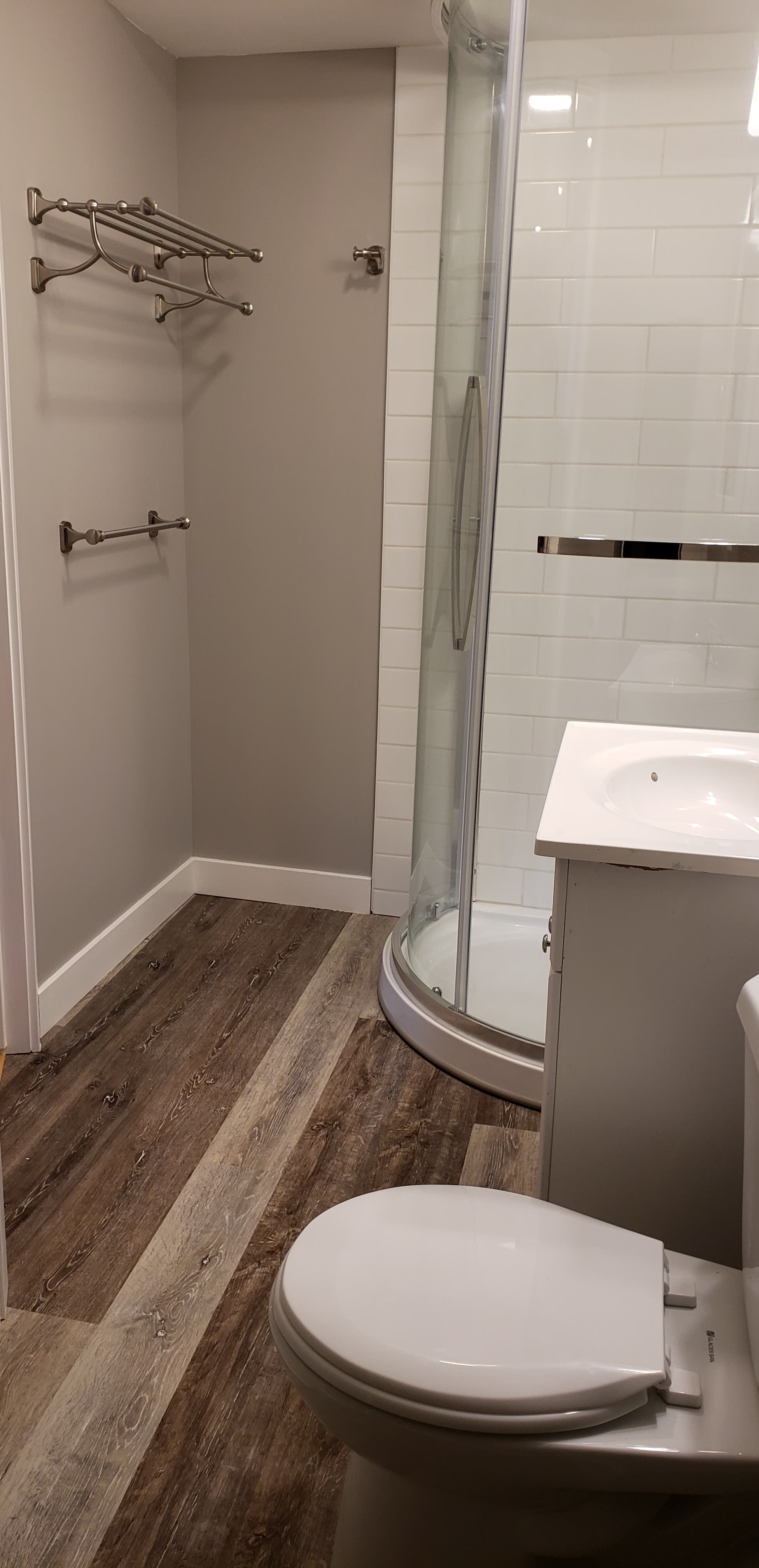 A renovated bathroom with a curved glass shower.