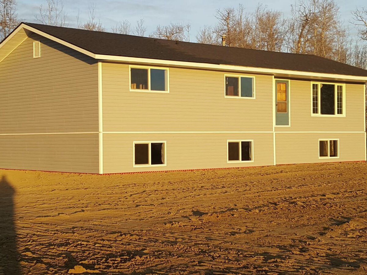 A finished house standing on raw, unlandscaped earth in Red Deer County.